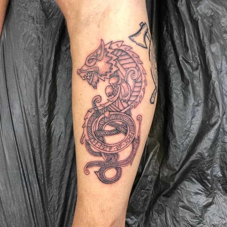 Forearm tattoo featuring Fenrir in a Nordic knotwork style, surrounded by runes, Vegvísir, and intricate Celtic patterns