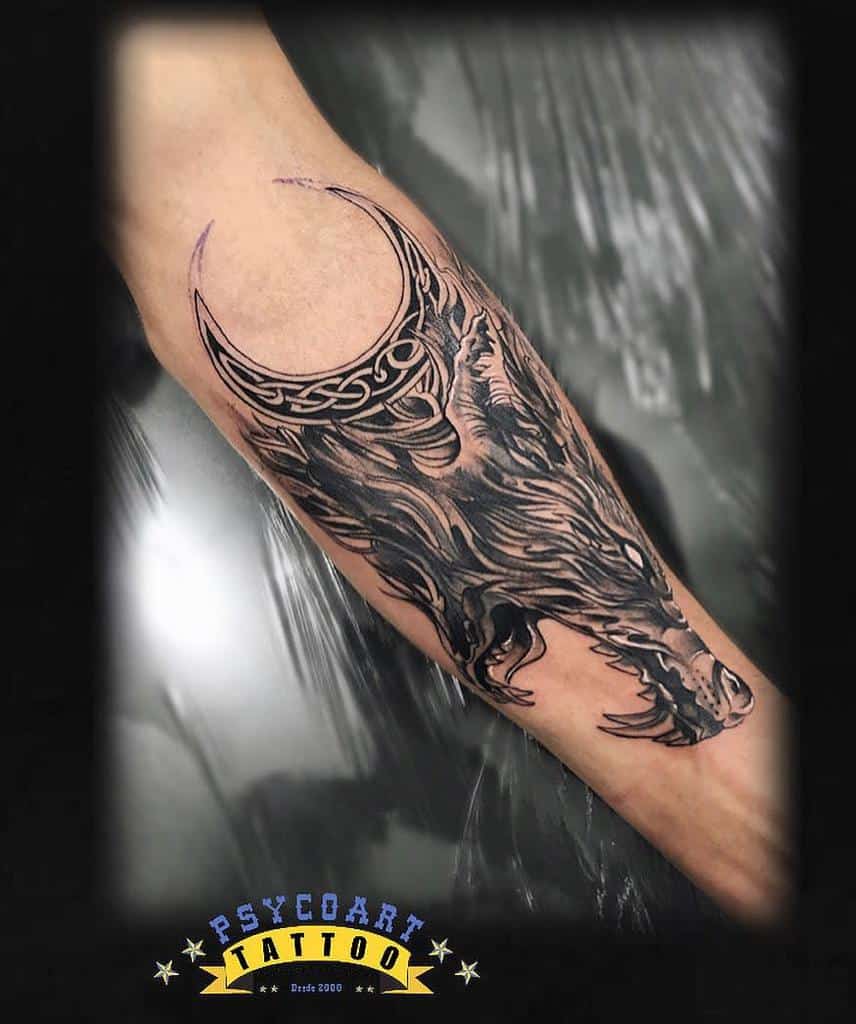 Forearm tattoo featuring Fenrir's head in bold blackwork, paired with a crescent moon and intricate Celtic knotwork