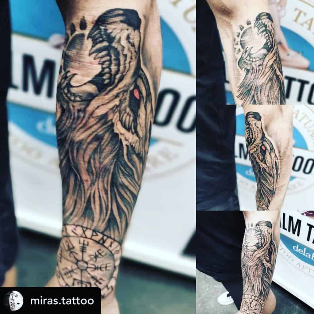 Forearm tattoo depicting Fenrir with fiery details, glowing red eyes, and runic symbols encircling a Vegvísir compass