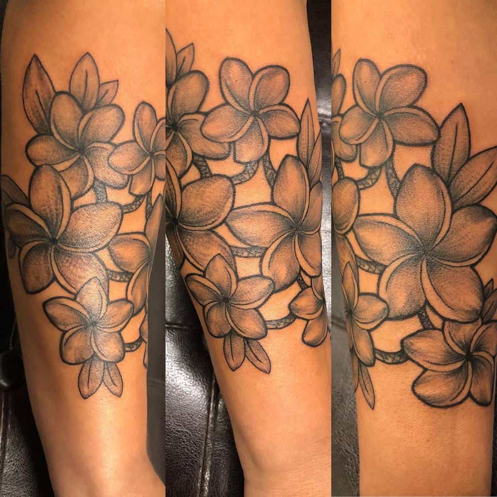 Tattoo of shaded plumeria flower clusters on an arm