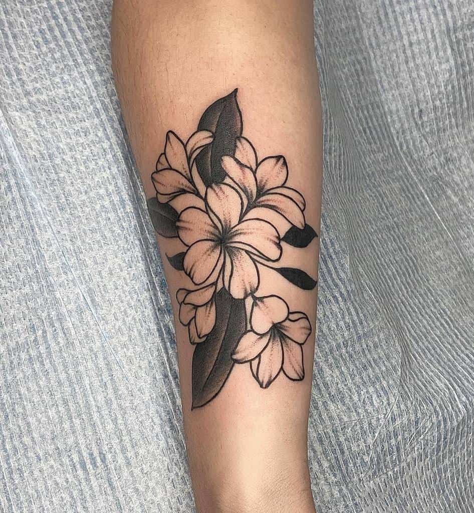 Plumeria tattoo with leaves on a forearm