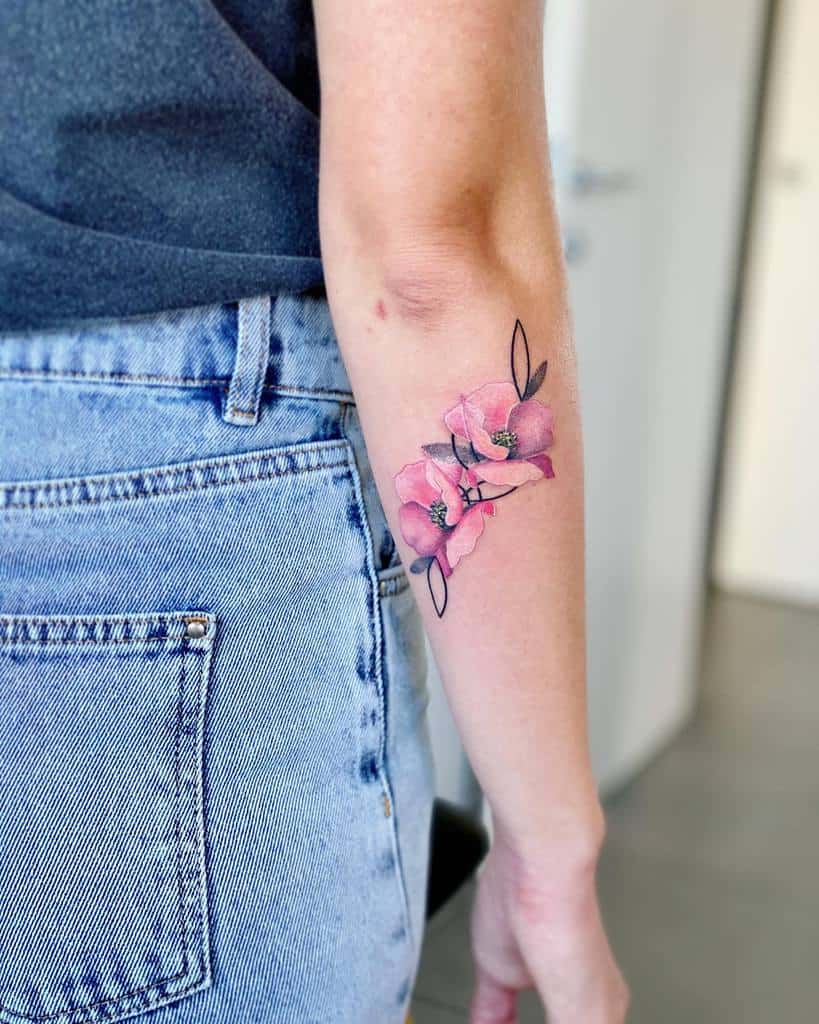 Delicate tattoo on the forearm featuring pink watercolor-style flowers with fine black outlines and minimal greenery