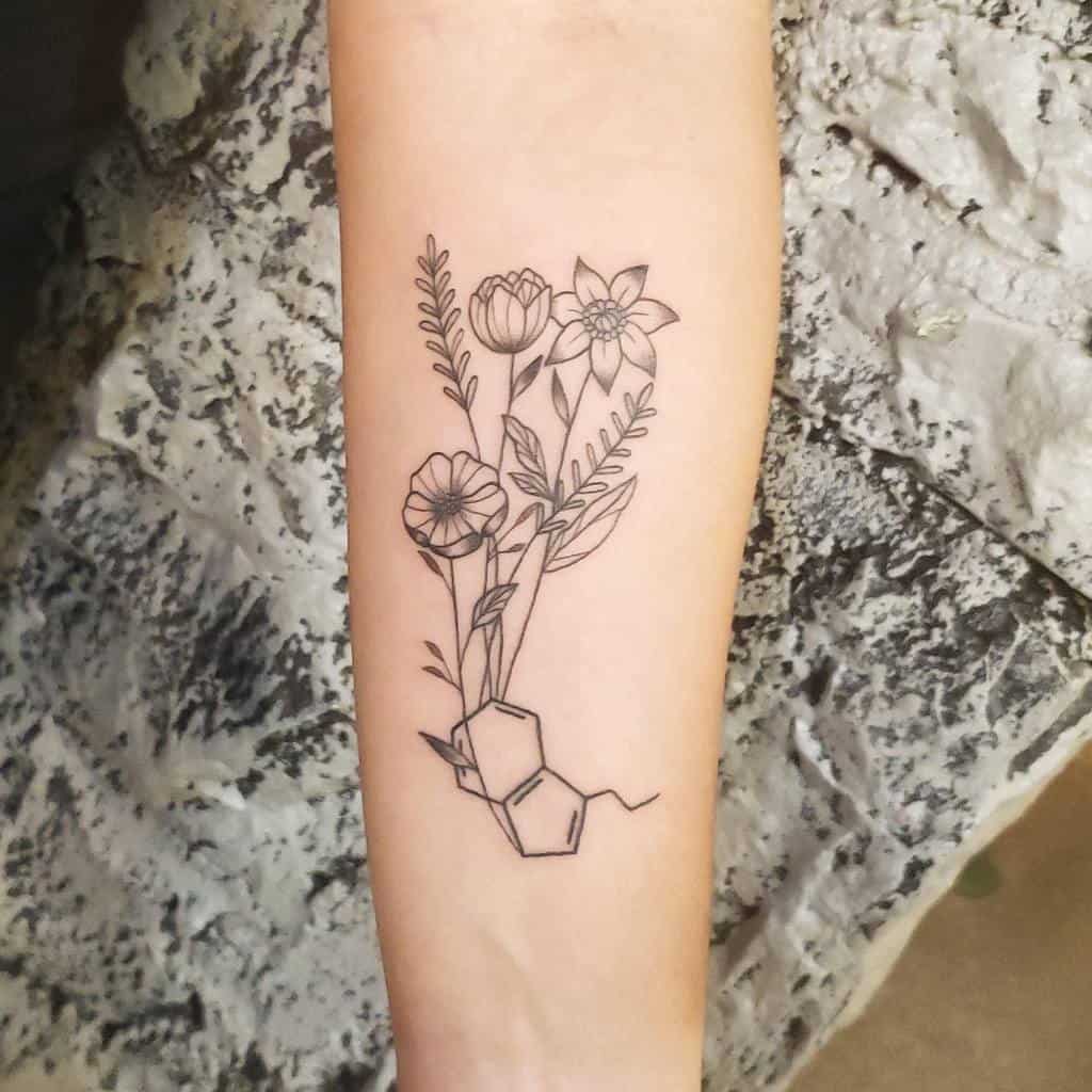 Simple serotonin molecule tattoo with delicate wildflowers on the forearm in black line art style