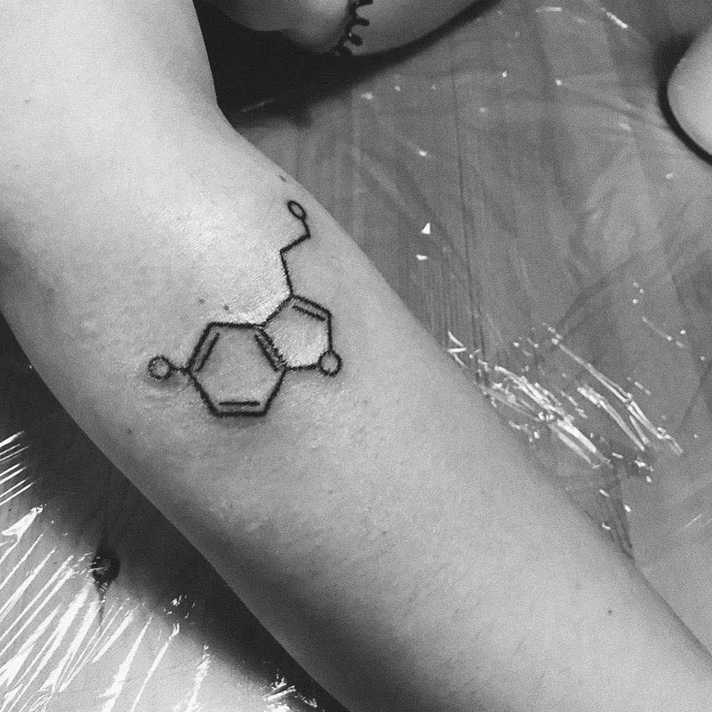 Black and white tattoo of serotonin's chemical structure on an arm