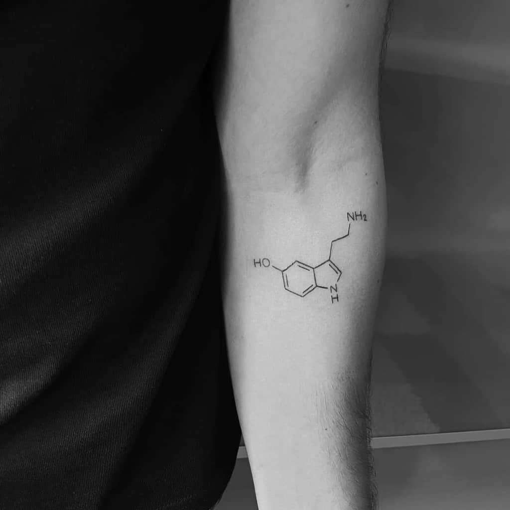 A black and white tattoo of a serotonin molecule on an arm, symbolizing balance and happiness