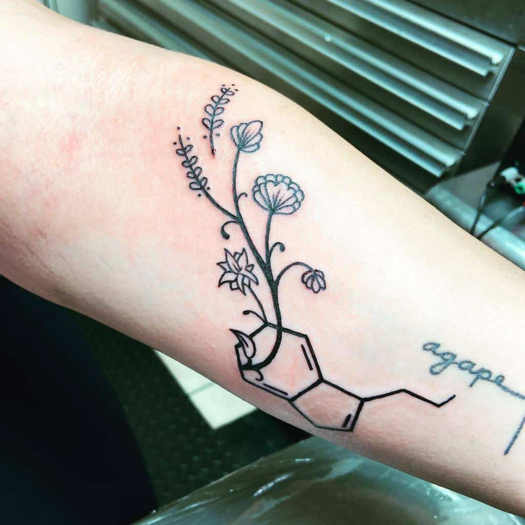An arm tattoo showcasing flowers blooming from a serotonin chemical structure