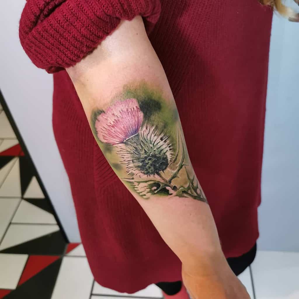 Forearm tattoo of a vibrant pink and green thistle