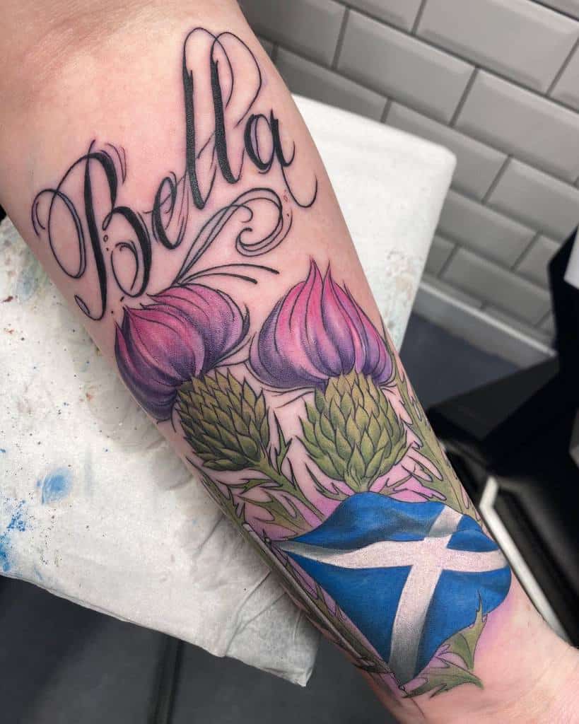Tattoo of "Bella" elegantly intertwined with vibrant thistles and a proud Scottish flag gracing the forearm