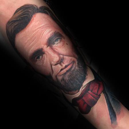 Tattoo of Abraham Lincoln with a bow tie on an arm, set against a black background