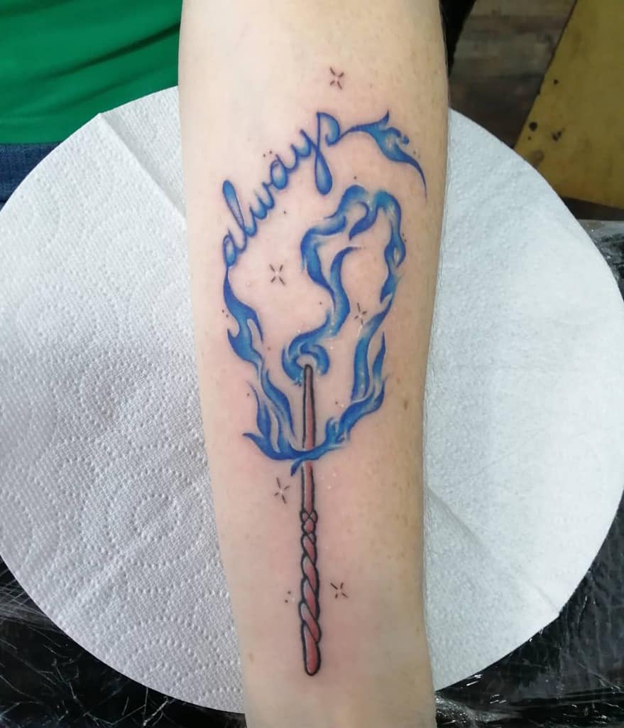 Harry Potter-inspired forearm tattoo with a wand emitting blue flames forming 'always,' symbolizing magic and eternal love