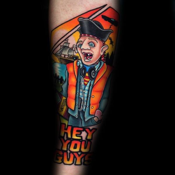 Vibrant tattoo of Sloth from The Goonies wearing a pirate hat and orange vest, with "Hey You Guys" in bold letters and a pirate ship in the background.