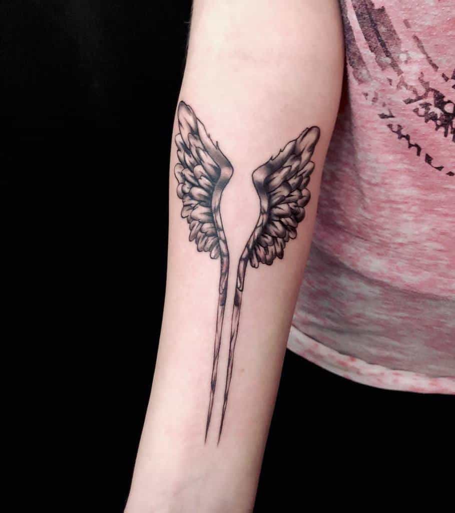 Minimalist angel wings tattoo featuring detailed feathers and a sleek design