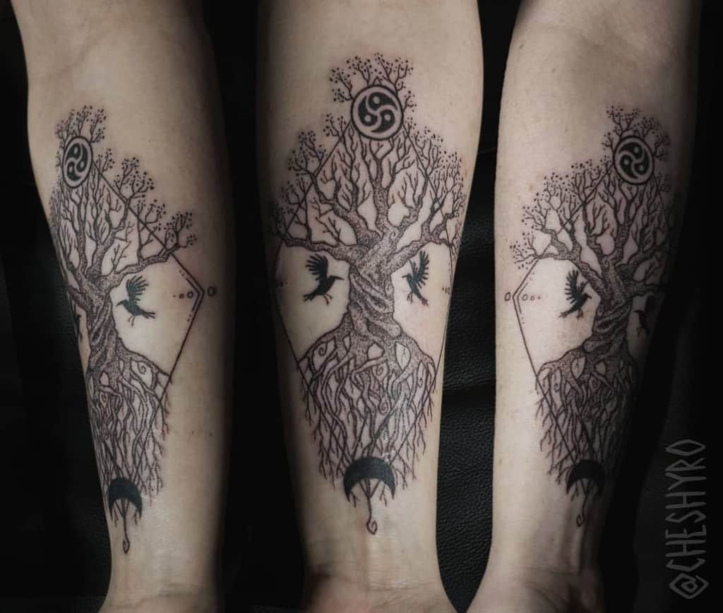 Intricate forearm tattoo featuring a tree of life, geometric patterns, crows in flight, and a crescent moon, symbolizing balance and transformation