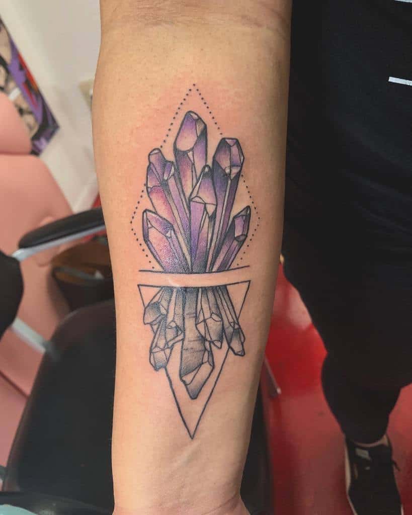 Forearm tattoo of vibrant purple crystals with geometric accents, symbolizing energy, healing, and spiritual growth