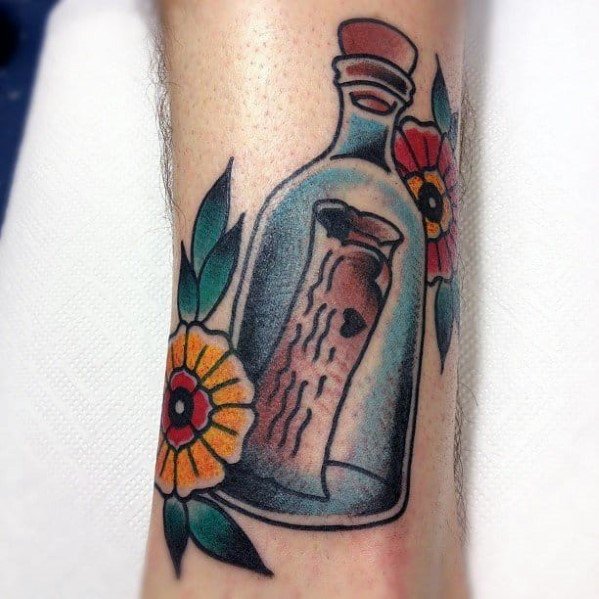 Tattoo of a message in a bottle and colorful flowers around it