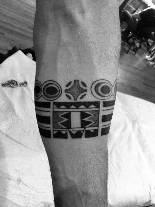 Geometric tribal tattoo featuring circular patterns and sharp angular designs on the forearm.