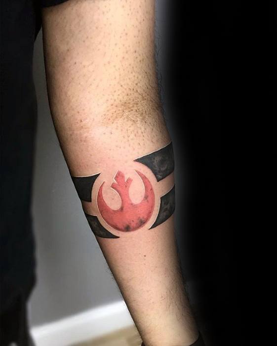 Rebel Alliance tattoo on the forearm, featuring a bold red symbol with black armbands wrapping around the arm.