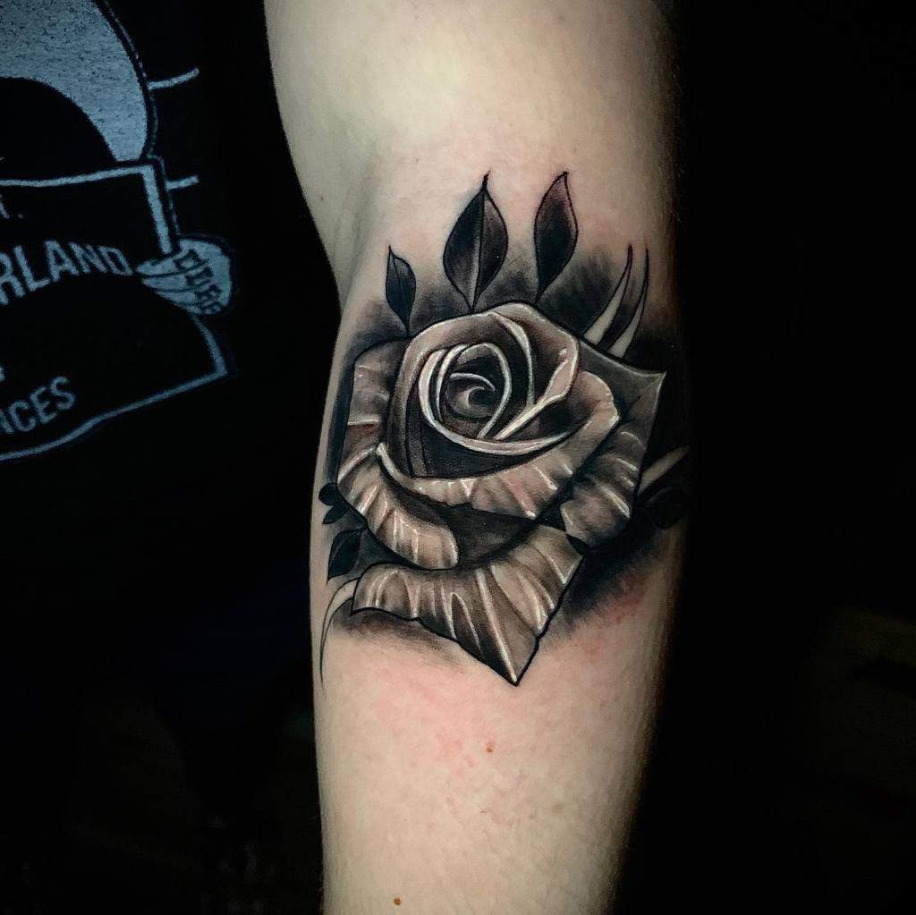 A black and gray rose tattoo on an arm