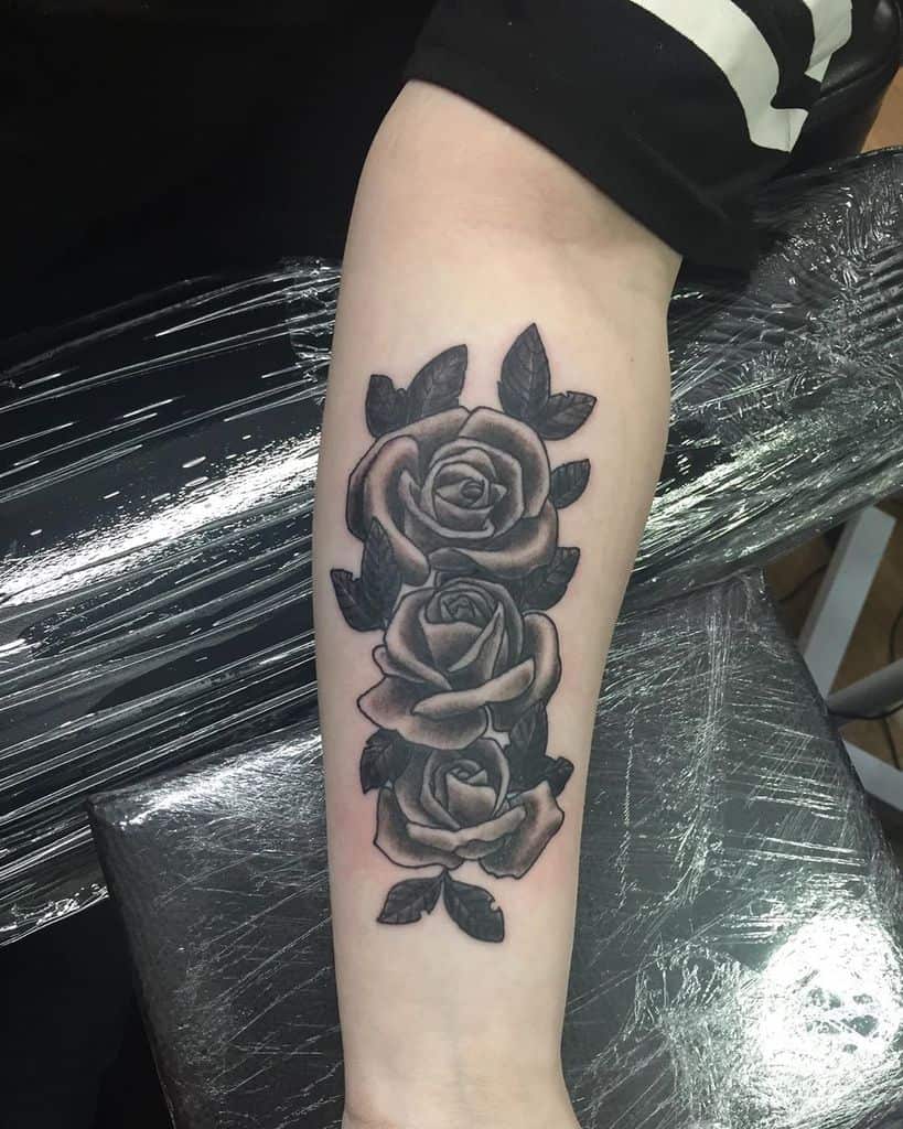 Tattoo of three black and gray roses on a forearm