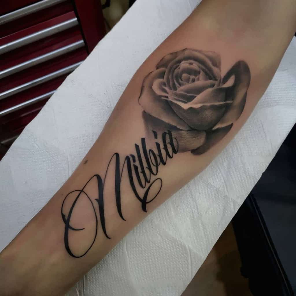 Tattoo of a rose and cursive text on a forearm