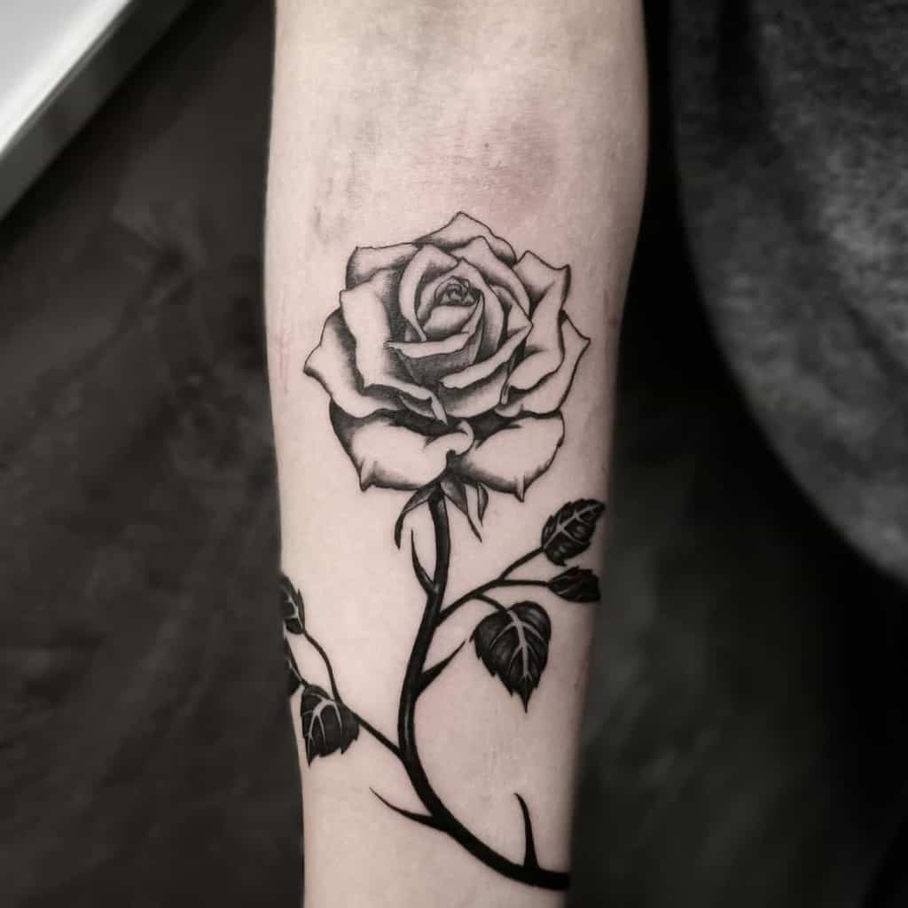 A detailed black rose blooms on the forearm, its leaves meticulously etched to enhance the intricate design