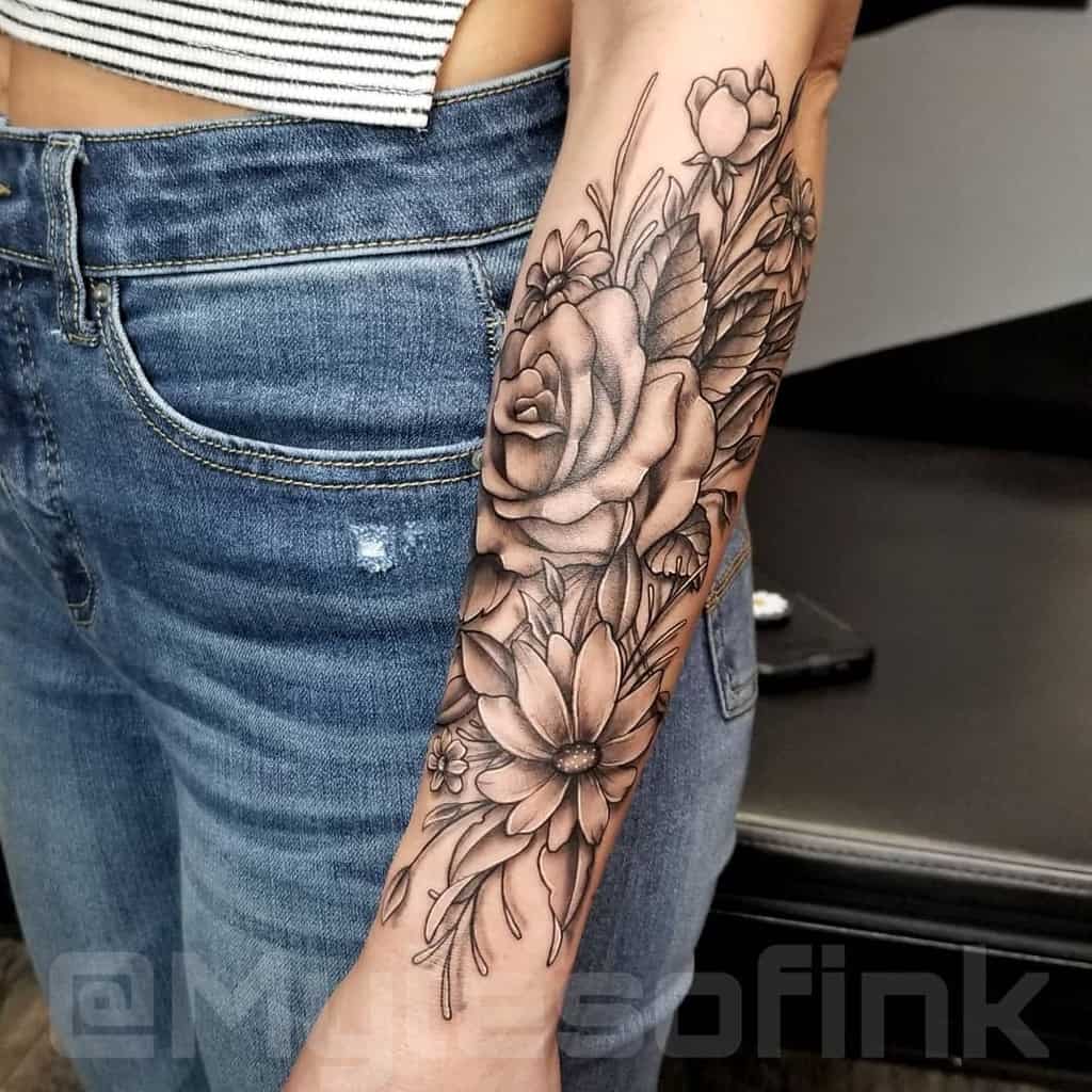 A stunning floral tattoo sleeve graces the forearm, featuring intricate roses and leaves