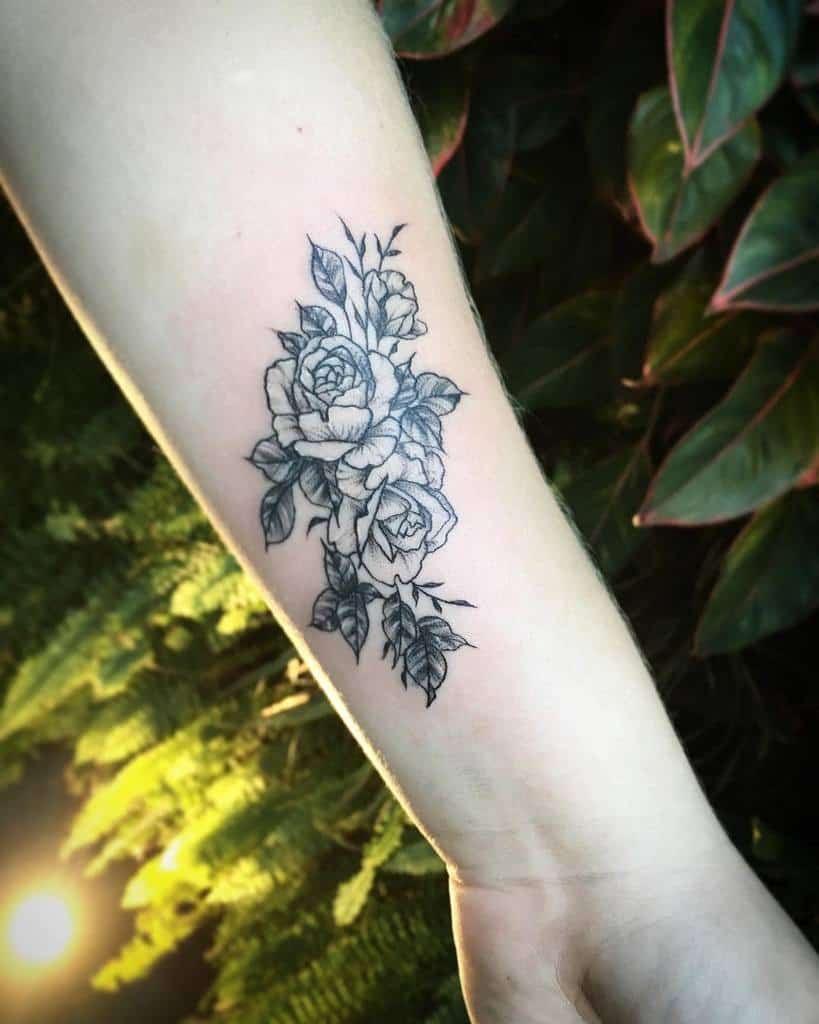 A stunning black and white rose tattoo graces the forearm