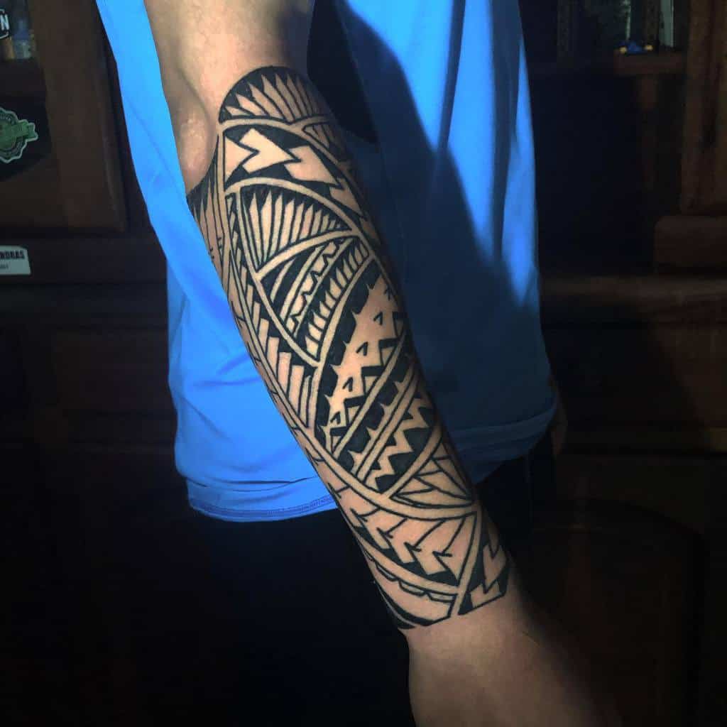 A man with a tribal-style tattoo on his forearm