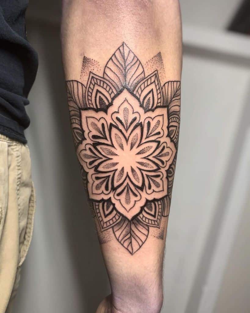 Intricate mandala tattoo on forearm with black and grey shading and geometric patterns