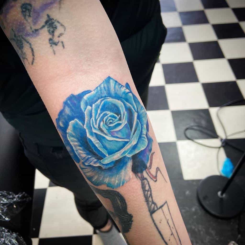 A stunning arm tattoo featuring a vibrant blue rose