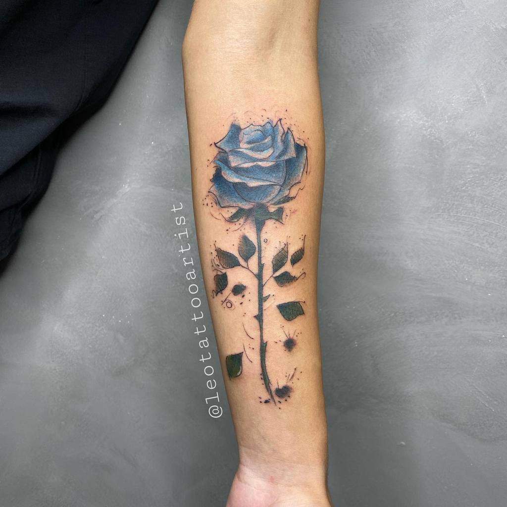 A striking tattoo of a blue rose blooms on the forearm, enhanced by dynamic splatter effects