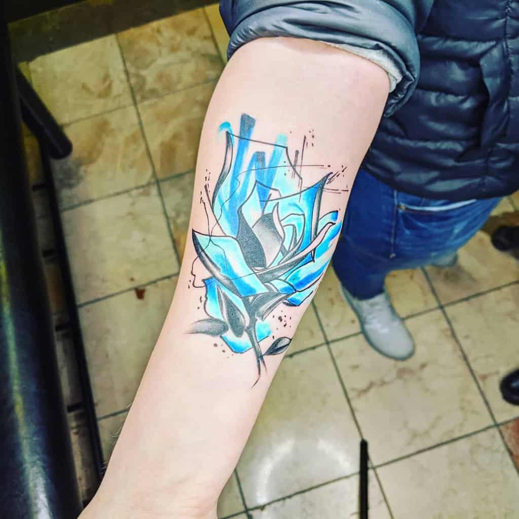 A creative and abstract blue rose tattoo on the forearm, with geometric shapes and black shading, giving it a modern, artistic flair