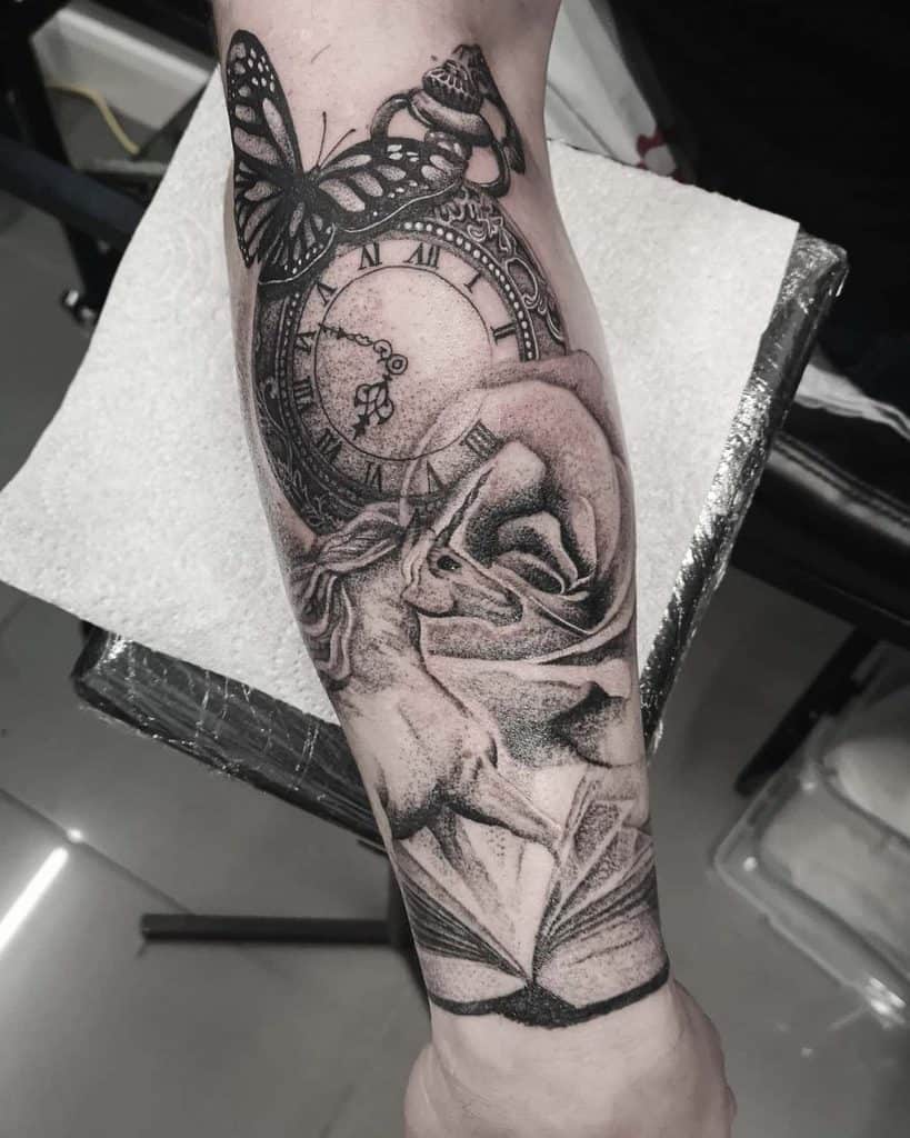 Black and grey forearm tattoo featuring a detailed clock, butterfly, rose, an open book, and a unicorn, blending time, nature, and fantasy themes.