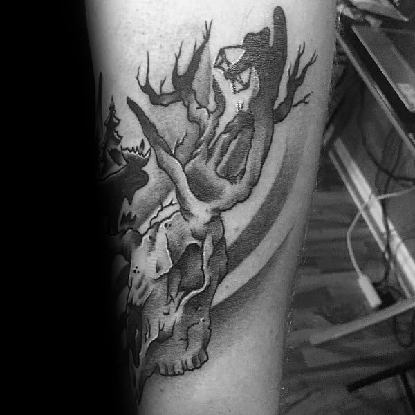 Black and grey tattoo of a deer skull with antlers transforming into a forest scene, featuring a bowhunter in a tree stand.