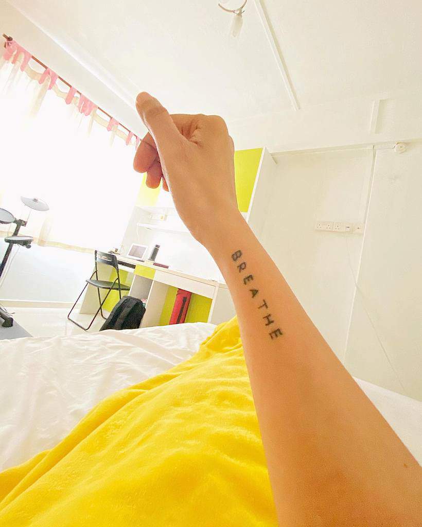 The arm adorned with a "BREATHE" tattoo