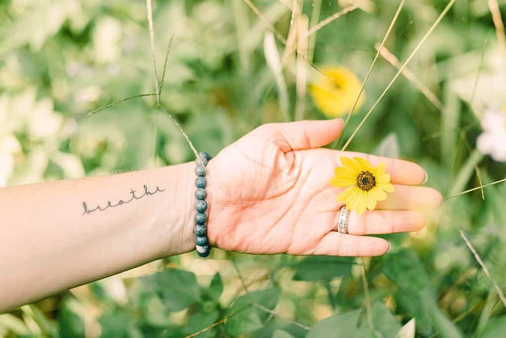 A wrist adorned with a "breathe" tattoo