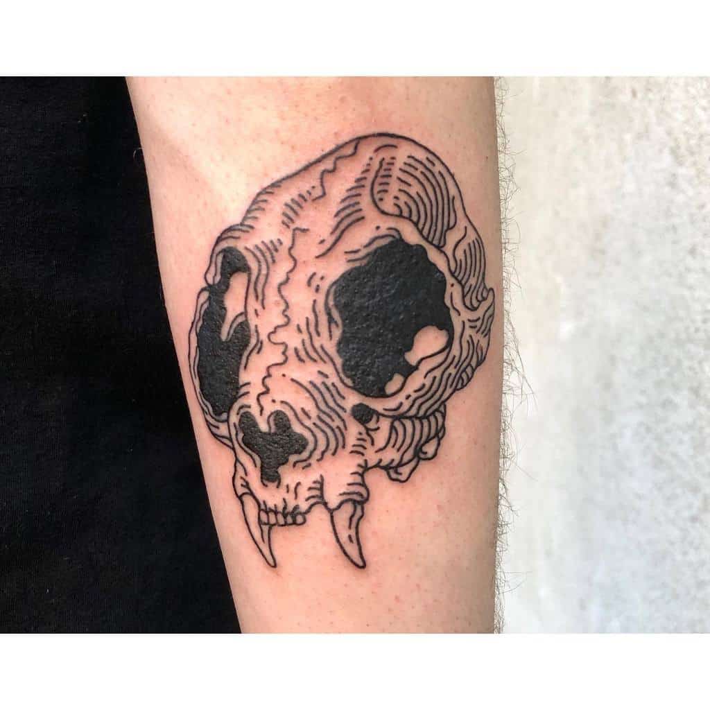 A tattoo of a detailed cat skull with dark shading on an arm