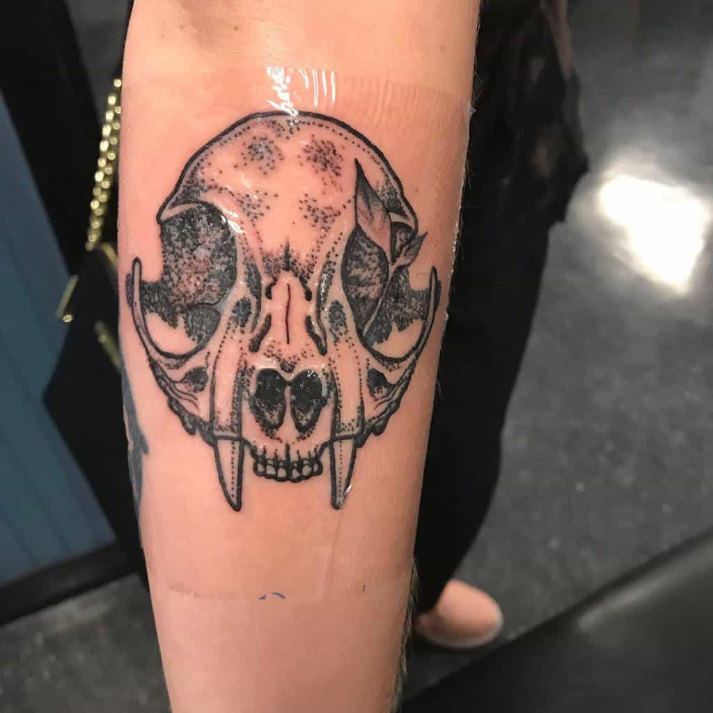 Tattoo of a detailed cat skull gracing a person's forearm