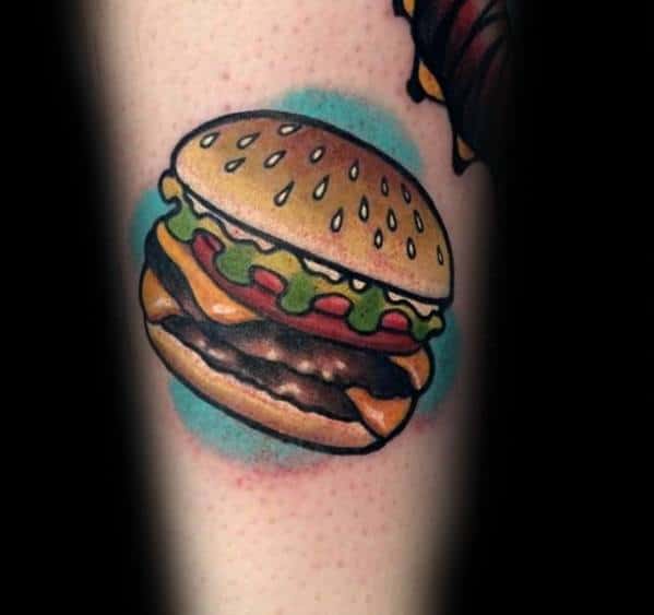 A cheeseburger tattoo with lettuce and tomato, encircled by a blue ring on skin