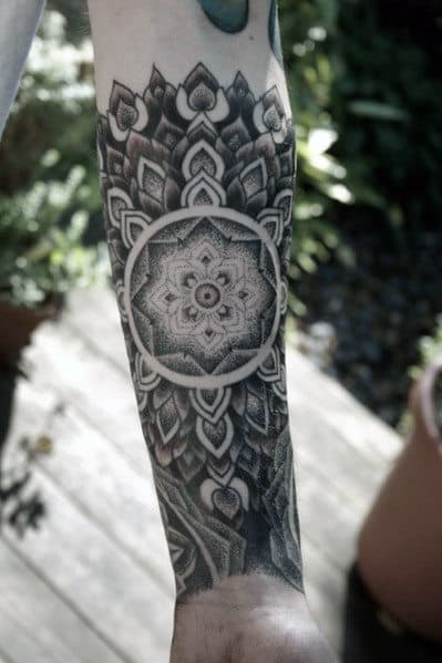 Detailed black and gray mandala tattoo on a person's forearm