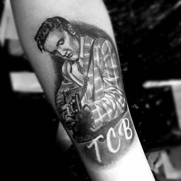 Black and grey Elvis Presley tattoo of him playing guitar, wearing a plaid jacket with the letters “TCB” featured below.