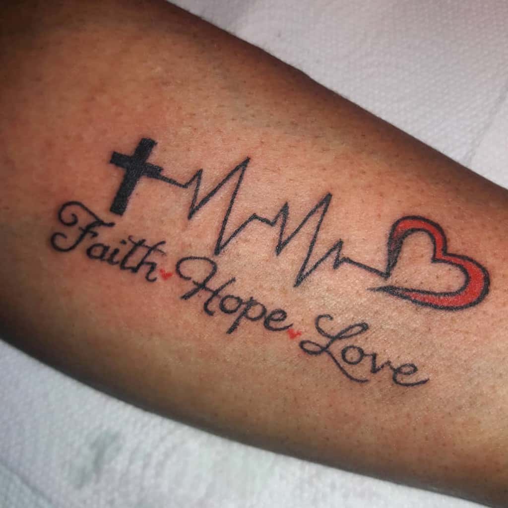 A tattoo featuring a cross, heartbeat line, and heart intricately woven with the words "Faith Hope Love" graces the arm, embodying a timeless trio of values and a testament to enduring beliefs and love