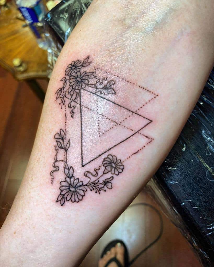 Tattoo of a triangle with floral designs on an arm