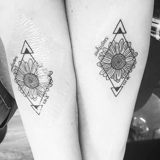 Two matching sunflower tattoos with geometric designs on skin, featuring text and triangles above and below the flowers