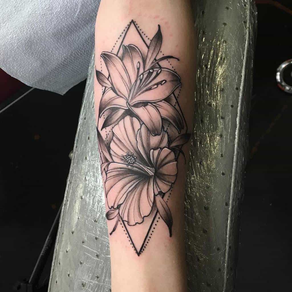 Black and grey floral tattoo of lilies on a forearm with a geometric diamond shape background