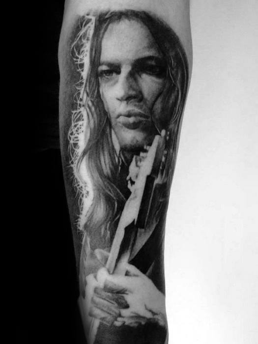 Portrait tattoo of a long-haired musician holding a guitar, showcasing intricate shading and lifelike detail