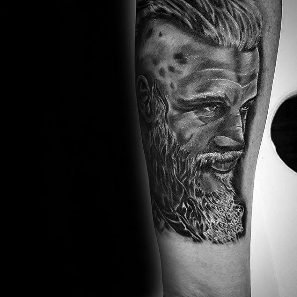 Realistic tattoo of a bearded man with slicked-back hair on an arm