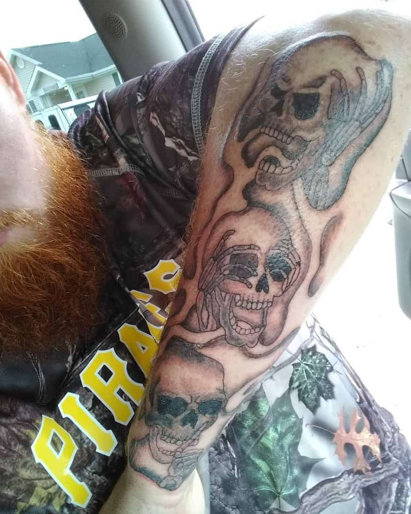 Forearm tattoo of three expressive skulls in a melted design, representing 'Hear No Evil, See No Evil, Speak No Evil'