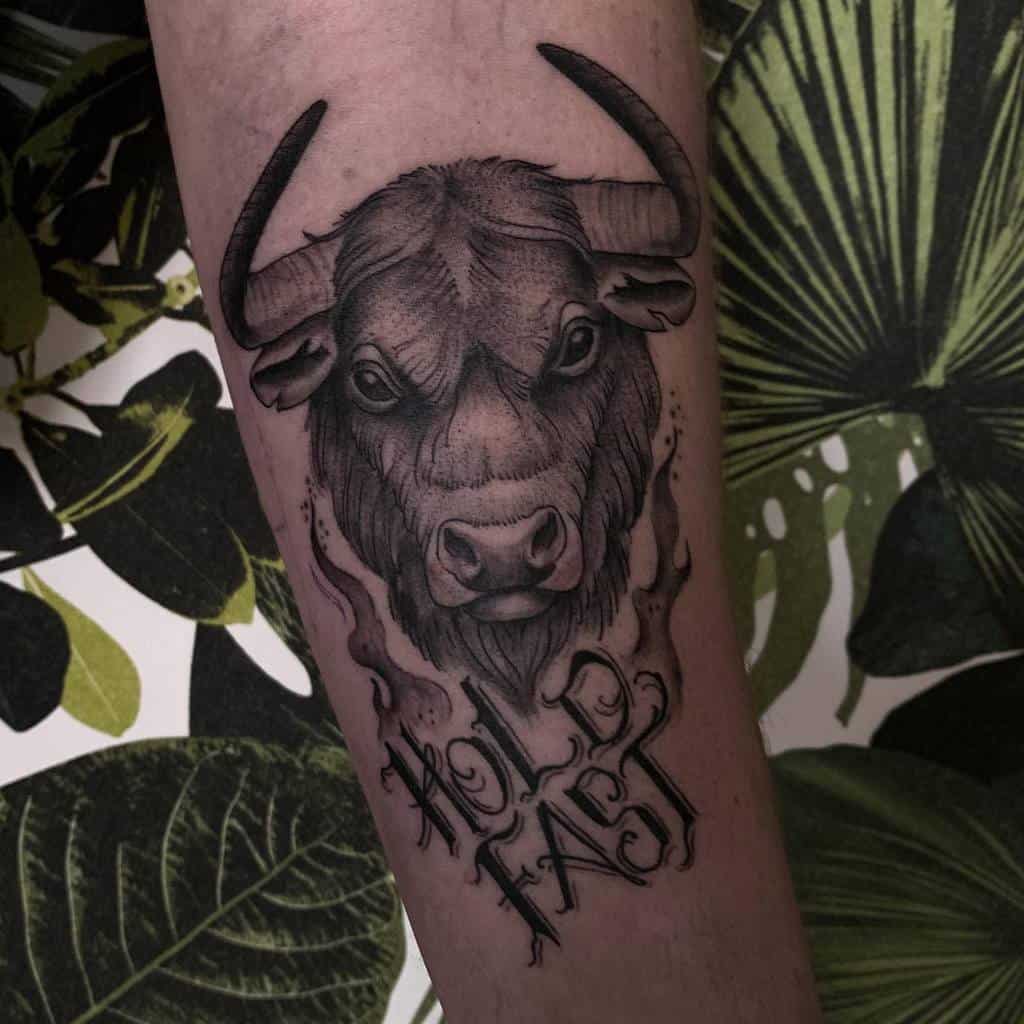 Tattoo of a bull's head with the words "Hold Fast" on an arm