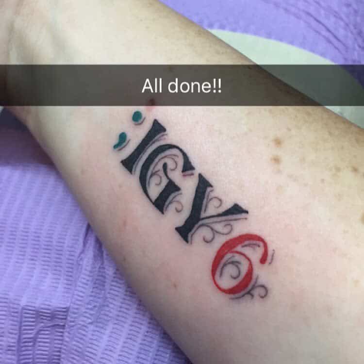 Forearm tattoo with stylized text ";IGY6" in black and red ink